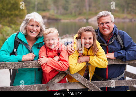 Großeltern und Enkel lehnte sich auf einem hölzernen Zaun in der Landschaft lachen, Lake District, Großbritannien Stockfoto