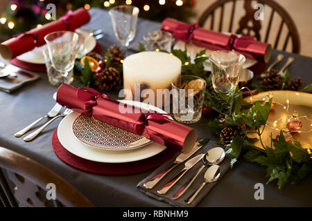 In der Nähe von Weihnachten Tischdekoration mit Knallbonbons arrangiert auf Platten und roten und grünen Tisch Dekorationen, Erhöhte Ansicht Stockfoto