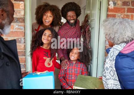 Die großeltern von Familie begrüßt, wie Sie ankommen zu besuchen und an Weihnachten mit Geschenken Stockfoto