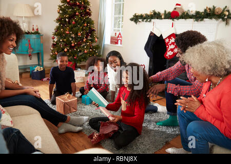 Tochter Eröffnung Geschenk als Multi-Generation Familie Weihnachten feiern zu Hause zusammen Stockfoto