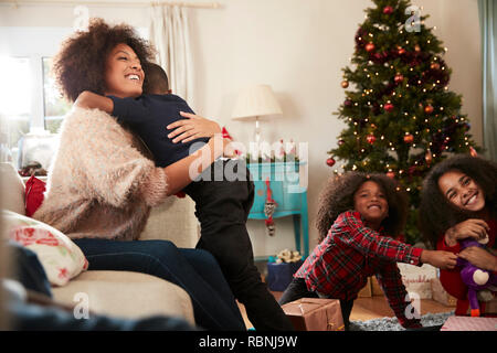 Mutter und Sohn umarmen als Familie Weihnachten feiern zu Hause zusammen Stockfoto