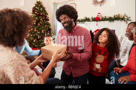 Paar den Austausch von Geschenken wie Multi-Generation Familie Weihnachten feiern zu Hause zusammen Stockfoto
