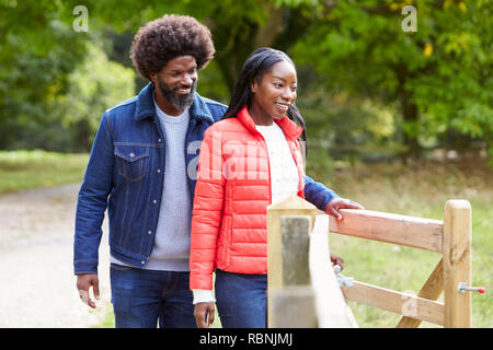 Mann Öffnen eines Tores für seine Freundin bei einem Spaziergang in dem Land, in der Nähe Stockfoto