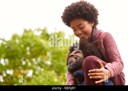Schwarz im mittleren Alter Mann seinen Sohn auf seinen Schultern im Park an einander suchen, Nahaufnahme, niedrigen Winkel Stockfoto