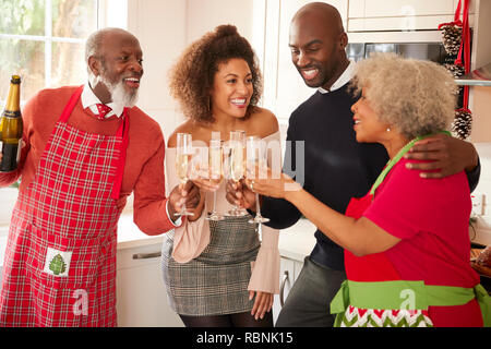 Multi-ethnischen nach Familie, und ein Toast mit Champagner auf Weihnachten zu feiern, während das Abendessen gemeinsam in der Küche, in der Nähe Stockfoto