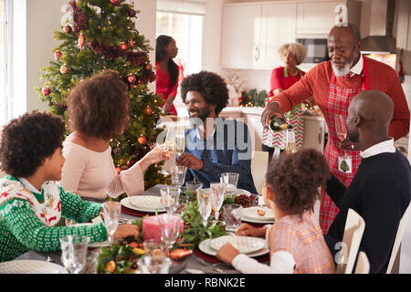 Familie sprechen und die Gläser auf den Tisch während einer Generation, gemischten Rennen Familie Weihnachtsfeier Stockfoto