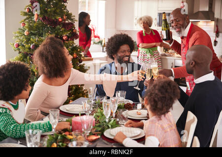 Familie sprechen und die Gläser auf den Tisch während einer Generation, gemischten Rennen Familie Weihnachtsfeier Stockfoto