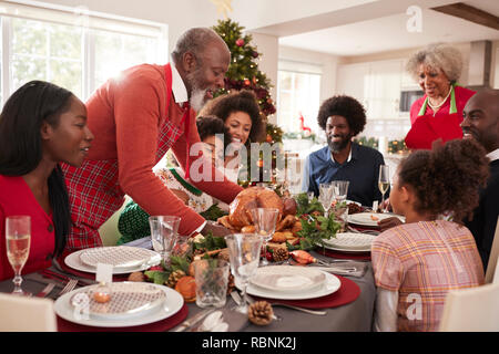 Großvater, der Truthahn auf den Tisch während einer Generation, gemischten Rennen Weihnachten mit der Familie zu feiern, in der Nähe Stockfoto