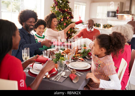 Gemischte Rasse, multi-generation Familie Spaß Cracker ziehen am Weihnachtsessen Tabelle Stockfoto