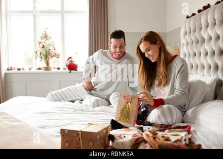 Aufgeregt Paar im Bett zu Hause öffnen Geschenke an Weihnachten Stockfoto