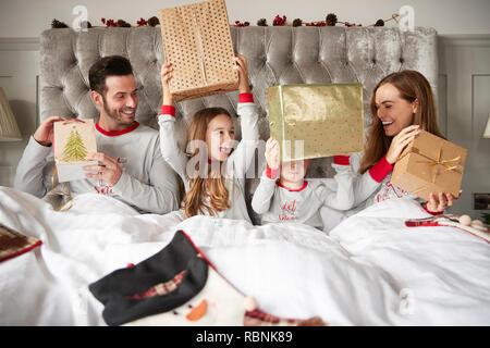 Aufgeregt Familie im Bett zu Hause öffnen Geschenke an Weihnachten Stockfoto