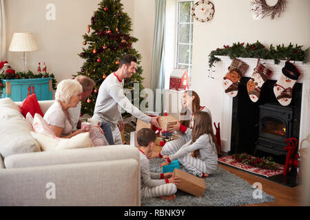 Drei Generation Familie tragen Schlafanzug in der Lounge zu Hause öffnen Geschenke an Weihnachten Stockfoto