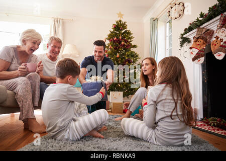 Drei Generation Familie tragen Schlafanzug in der Lounge zu Hause öffnen Geschenke an Weihnachten Stockfoto