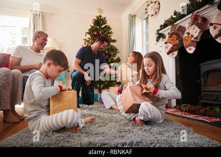 Drei Generation Familie tragen Schlafanzug in der Lounge zu Hause öffnen Geschenke an Weihnachten Stockfoto