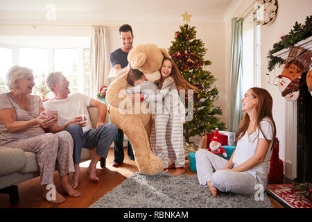 Kinder spielen mit riesigen Teddybär als Multi-Generation Familie Geschenke an Weihnachten Stockfoto