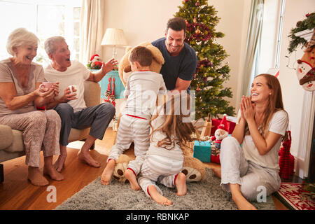 Kinder spielen mit riesigen Teddybär als Multi-Generation Familie Geschenke an Weihnachten Stockfoto