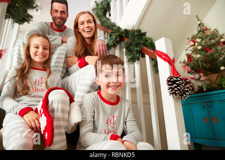 Portrait von Angeregten Familie tragen Schlafanzug Sitzen auf der Treppe am Weihnachtsmorgen Stockfoto