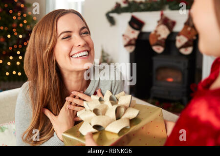 Aufgeregt, Mutter empfangen Weihnachtsgeschenk von Tochter zu Hause Stockfoto