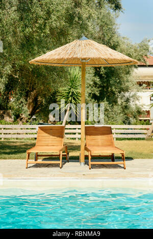 Sonnenliegen und Sonnenschirm am Pool in Griechenland Stockfoto