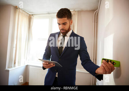 Männliche Realtor mit digitalen Tablet Messraum mit Laser messen. Stockfoto