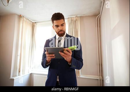 Männliche Realtor mit digitalen Tablet Messraum mit Laser messen. Stockfoto