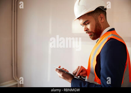 Surveyor in harten Hut und hohe Sichtbarkeit Jacke mit digitalen Tablet Durchführung eigener Prüfung Stockfoto