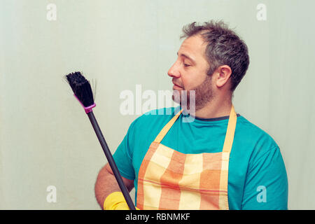 Emotionale bärtiger Mann mit einem Besen. Hellen Hintergrund. Stockfoto