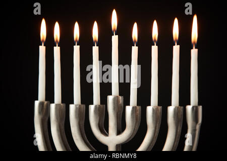 Kerzen auf Metall Hanukkah Menorah gegen Schwarze Studio Hintergrund Stockfoto