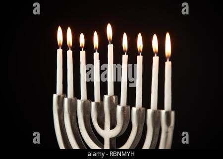 Kerzen auf Metall Hanukkah Menorah gegen Schwarze Studio Hintergrund Stockfoto