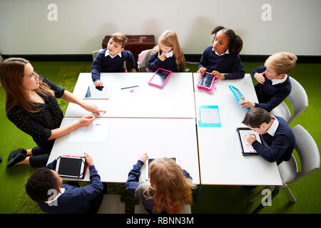 Ansicht der Grundschule Kinder sitzen um einen Tisch in der Klasse mit ihrer Lehrerin Stockfoto