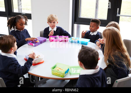 Ansicht der Grundschule Kinder sitzen gemeinsam an einem runden Tisch essen ihre Lunchpakete Stockfoto