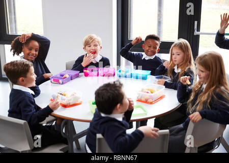 Ansicht der Grundschule Kinder sitzen gemeinsam an einem runden Tisch essen ihre Lunchpakete Stockfoto