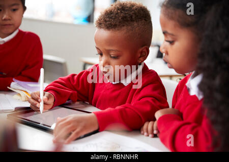 Drei Kindergarten Kinder sitzen am Schreibtisch in einem mit einem Tablet Computer und Stylus zusammen Klassenzimmer, selektiven Fokus Stockfoto