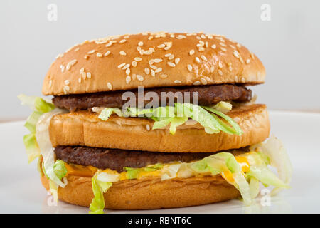 In der Nähe Bild von einem leckeren double Cheeseburger mit Rindfleisch, Cheddar, Salat in einem sesambrötchen Stockfoto