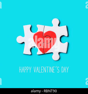 Nahaufnahme der beiden Teile eines Puzzles bilden ein Herz und der Text happy valentines Tag auf einem blauen Hintergrund Stockfoto