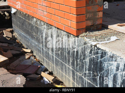 Abdichtung Grundmauern. Stiftung Abdichtung und Feuchtigkeitssperren Beschichtungen. Abdichtung Haus Stiftung mit Spray auf Teer. Haus Isolierung Stockfoto