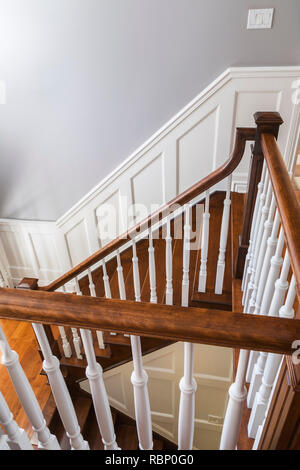 Kirschholztreppe und Geländer mit weißen Spindeln auf der oberen Etage in einem zeitgenössischen Haus im Landhausstil. Stockfoto