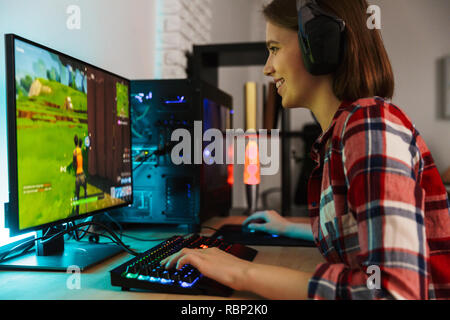 Mädchen Spieler am Tisch sitzenden aufgeregt, Online-Spiele auf einem Computer im Innenbereich Stockfoto