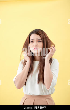 Junge asiatische Frau ihr Haar und enttäuschend Zustand ihrer Haare bürsten Stockfoto