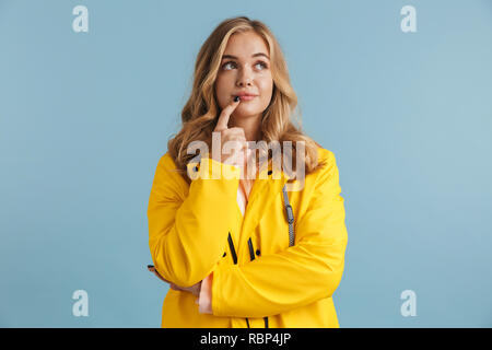 Foto der jungen Frau 20 s tragen gelbe Regenmantel nach oben über blau Hintergrund isoliert Stockfoto
