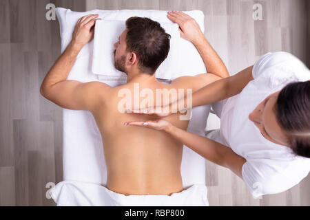 Nahaufnahme einer entspannten jungen Mann empfangen Schulter Massage Stockfoto