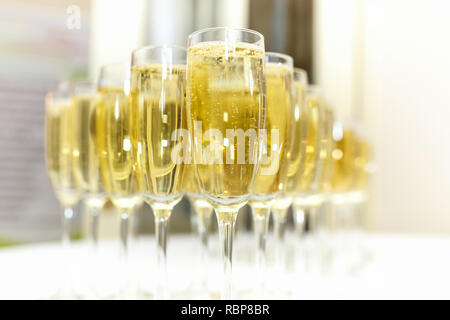 Menge unscharfer Gläser mit Champagner auf der Rezeption Partei Tabelle auf hellen Hintergrund Stockfoto