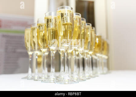 Menge unscharfer Gläser mit Champagner auf der Rezeption Partei Tabelle auf hellen Hintergrund Stockfoto