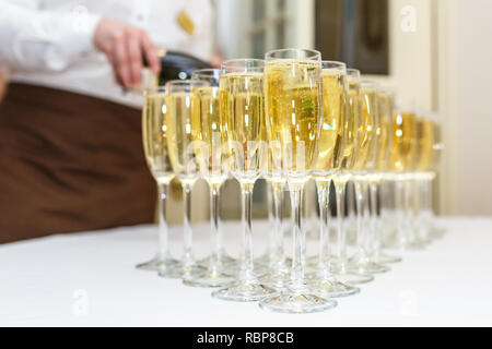 Menge unscharfer Gläser mit Champagner auf der Rezeption Partei Tabelle auf hellen Hintergrund Stockfoto