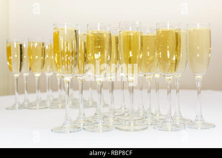 Menge unscharfer Gläser mit Champagner auf der Rezeption Partei Tabelle auf hellen Hintergrund Stockfoto