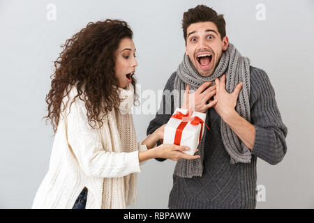 Bild der kaukasischen Mann und Frau Jubel beim Stehen mit Geschenkbox über grauer Hintergrund Stockfoto