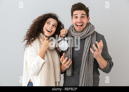 Bild der kaukasischen Paar Mann und Frau lächelnd, während sie Wecker über grauer Hintergrund Stockfoto