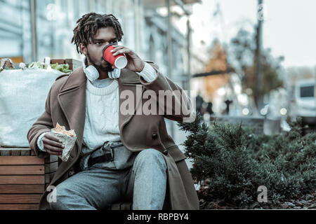 Ernsthafte junge männliche Person trinken heißen Kaffee Stockfoto