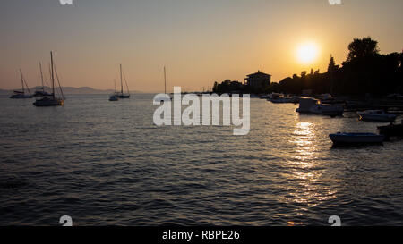 Mehrere Segelboote in der Bucht bei Sonnenuntergang verankert Mit der Küste in Silhouette in der Nähe von Zadar, Kroatien Stockfoto