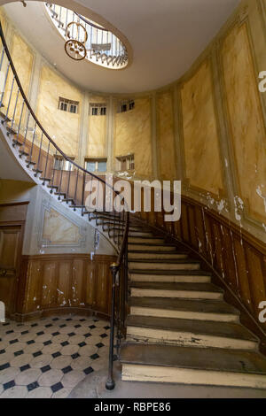 Gebogene Treppe im Eingangsbereich eines Gebäudes mit schwarzen und weißen Bodenfliesen Stockfoto